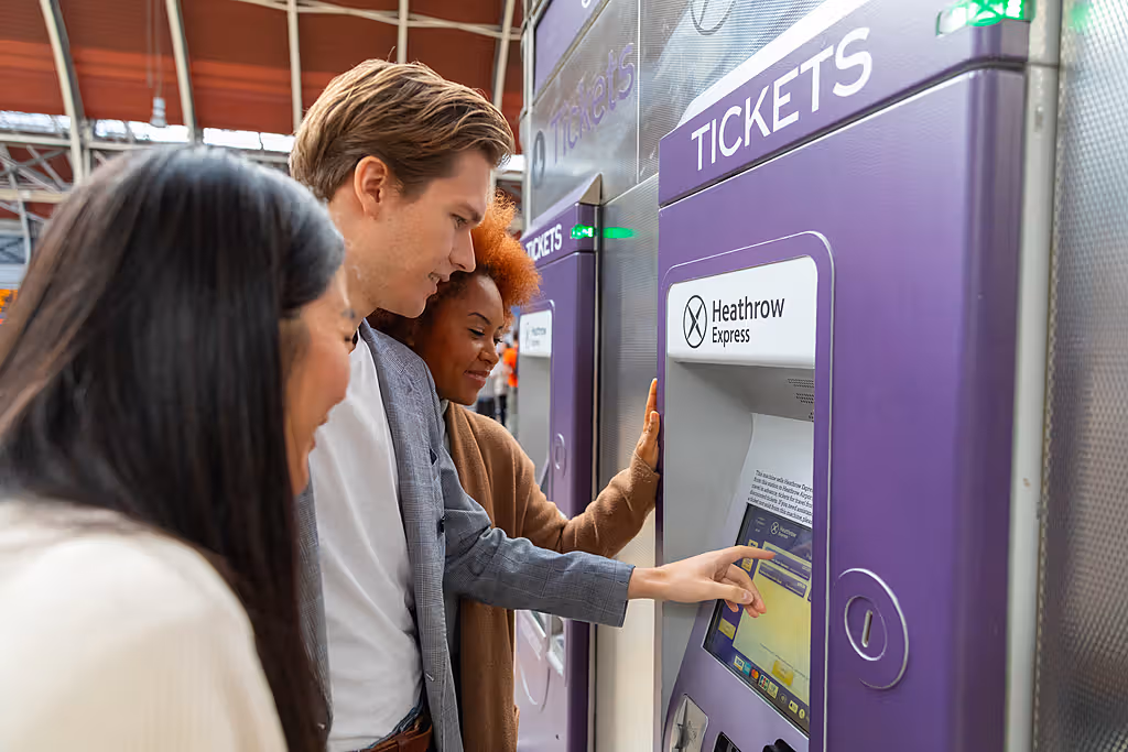A group of people buying tickets at a ticket machine